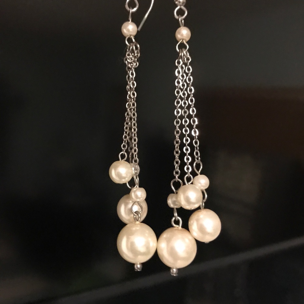 Long white pearl dangling earrings.