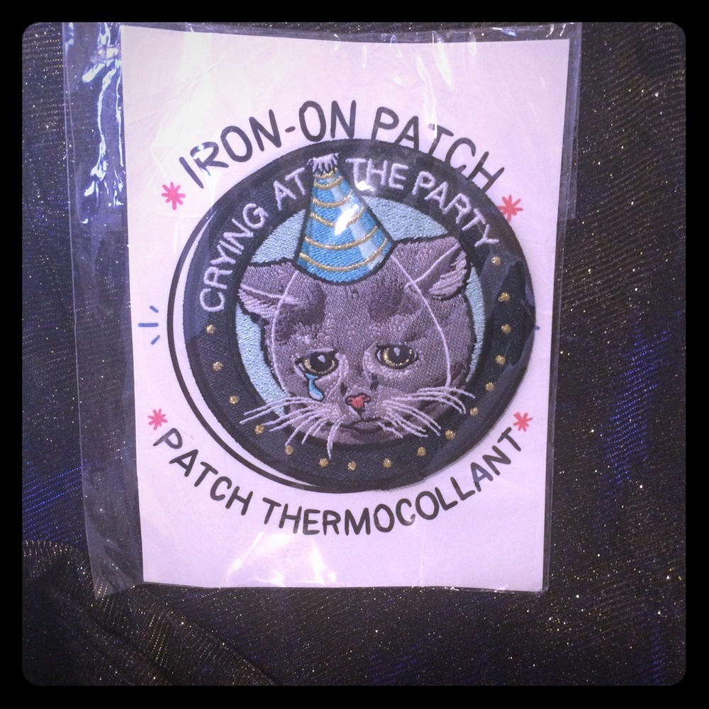 Iron-on patch with crying cat detail.