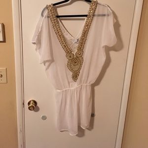 A white with gold beaded swimsuit cover.