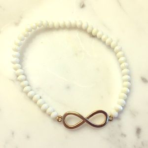 White beaded bracelet with gold eternity symbol