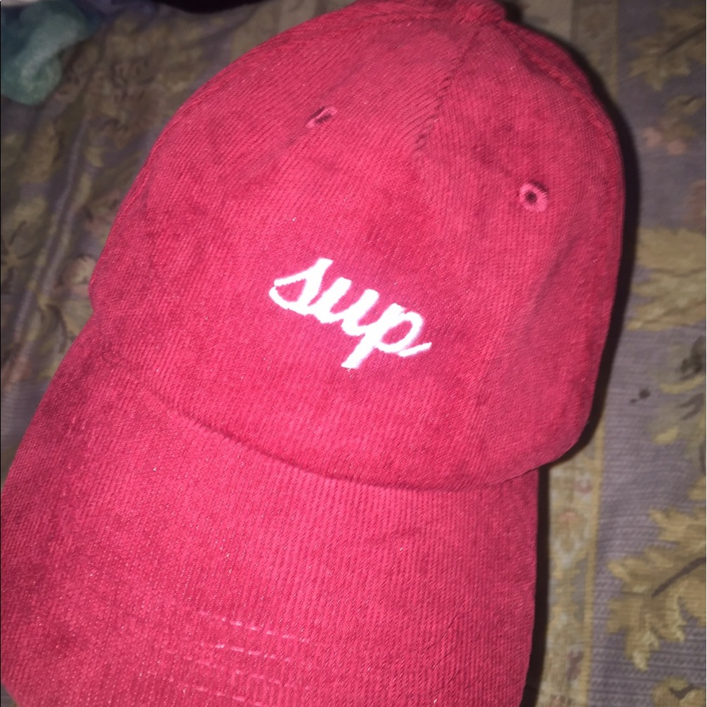 A red corduroy hat that says sup & bye