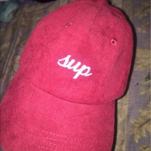 A red corduroy hat that says sup & bye