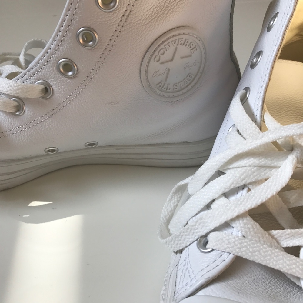 All white leather Converse sneakers.