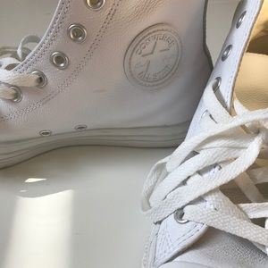 All white leather Converse sneakers.