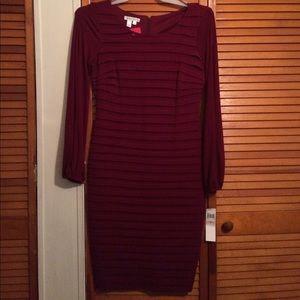 Burgundy dress with folds and sheer sleeves.