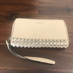Cream Coach wristlet with silver stud accents