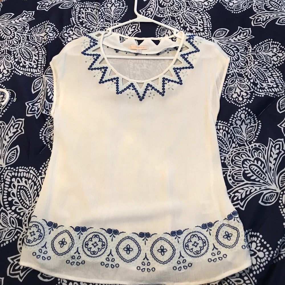 White sleeveless blouse with blue detail.