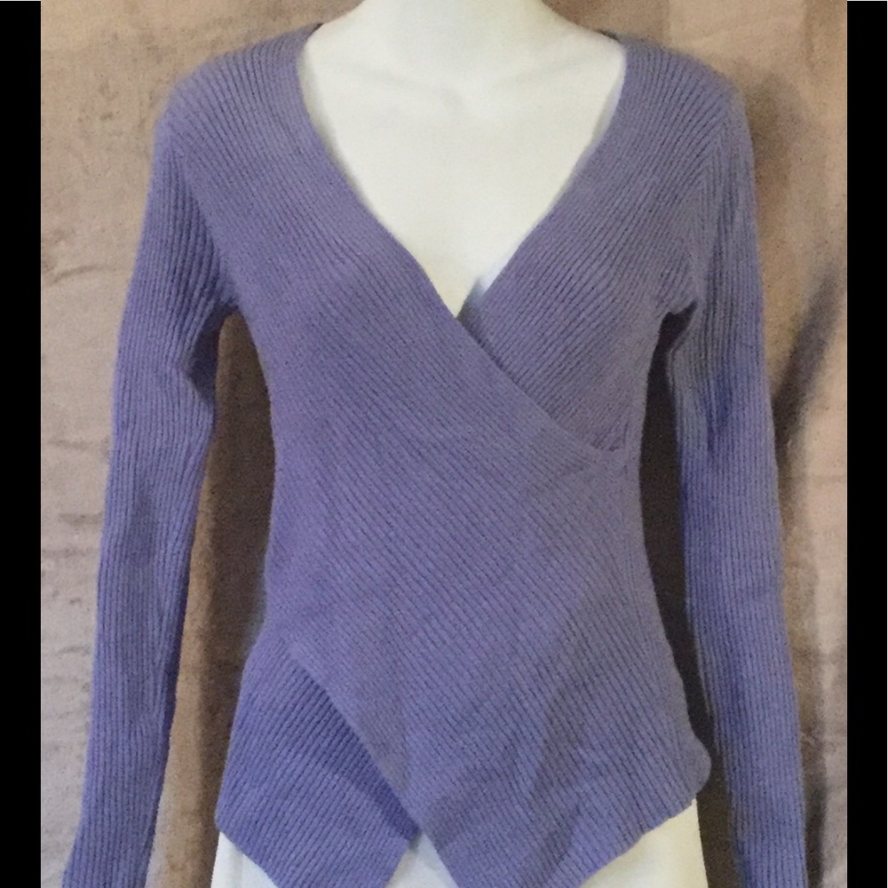 Figure hugging wraparound knit pullover blouse.