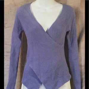 Figure hugging wraparound knit pullover blouse.