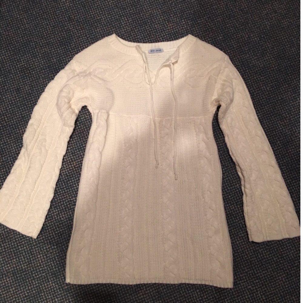 Small cableknit sweater with tie strings at neck.