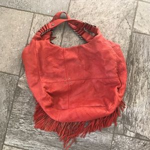 Red leather hobo bag with fringe detail.
