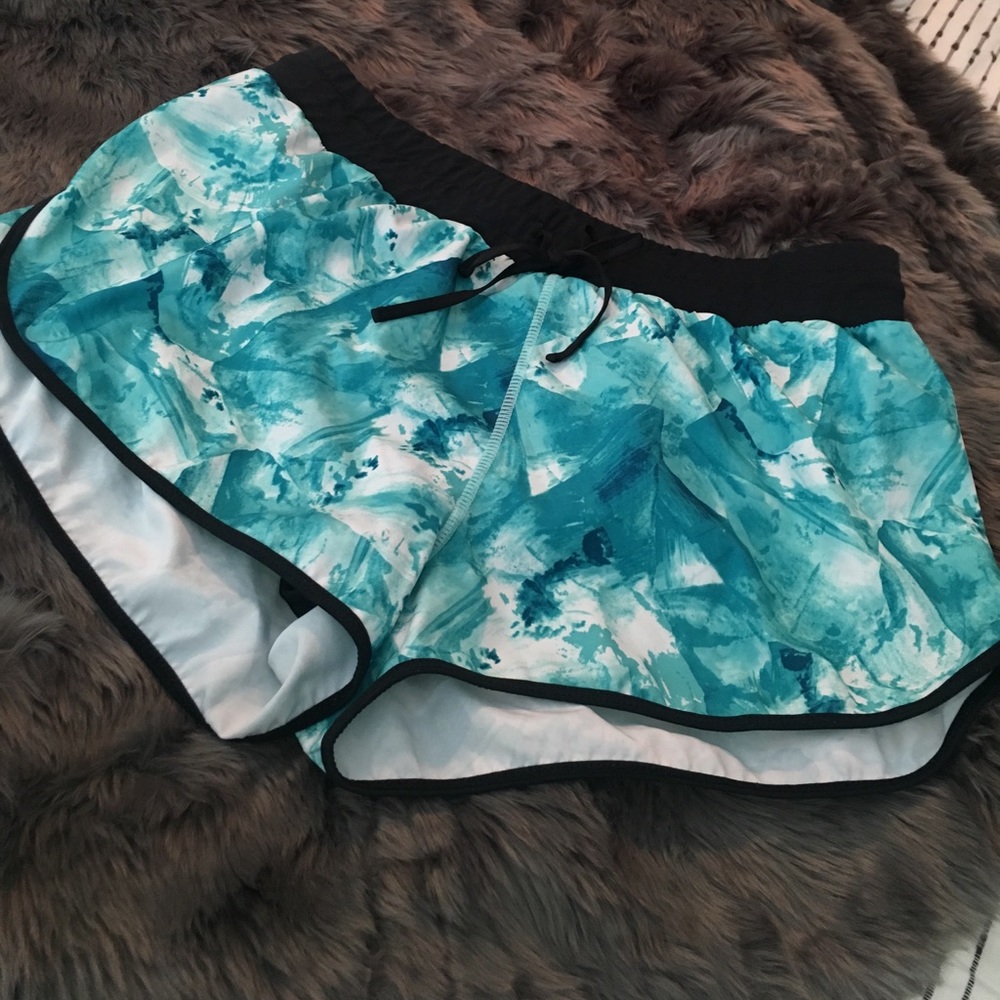 Fabletics running shorts in teal, white, and black