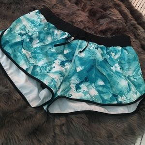 Fabletics running shorts in teal, white, and black