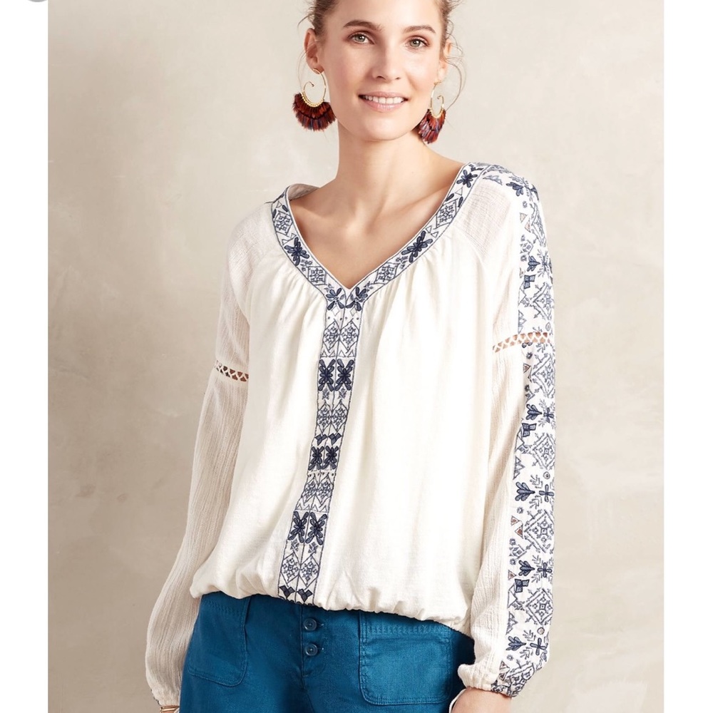 White blouse with blue embroidered detail.