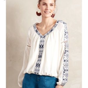 White blouse with blue embroidered detail.
