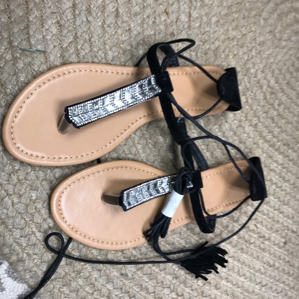 Lace up embellished black sandals with tassels.
