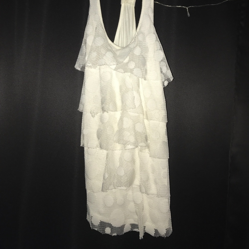 A cream white tank top with ruffles on the font.