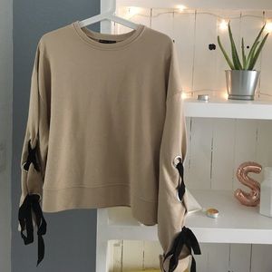 Tan sweater, lace-up black details on sleeves