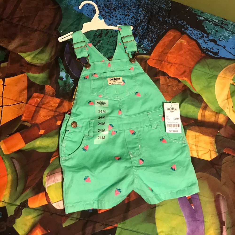 A pair of mint green overalls with strawberries