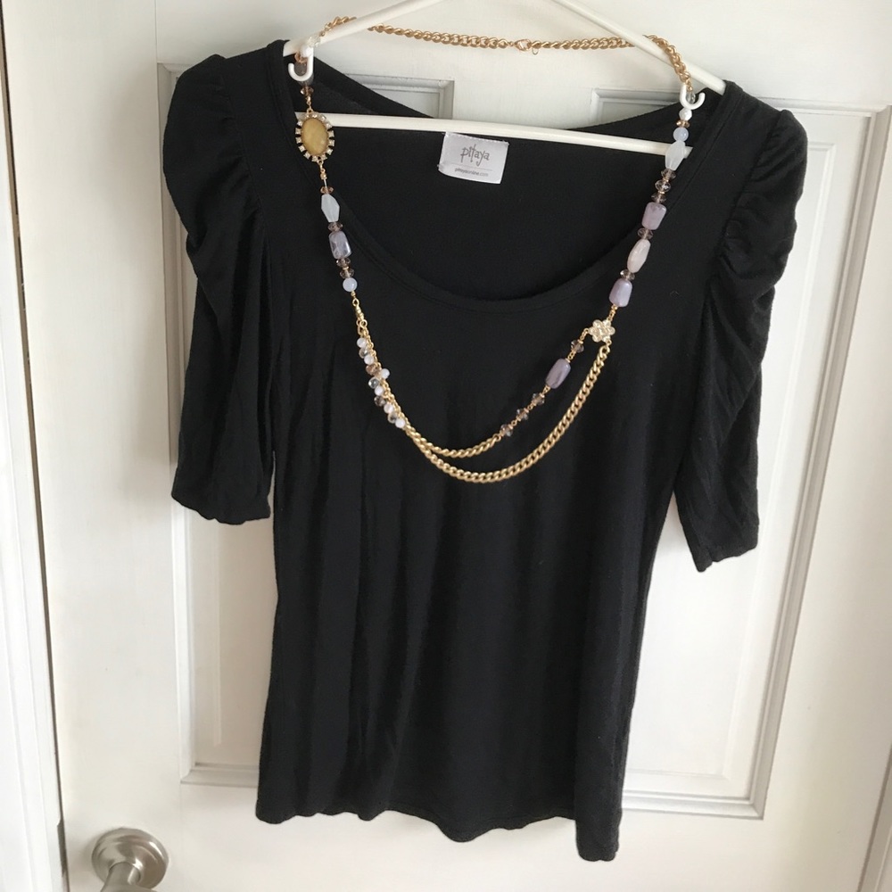 Black, scoop neck shirt with gold, gem necklace.