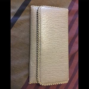 Dark gray wallet with gold metal embellished trim.