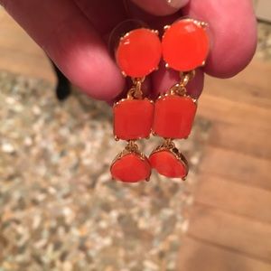 Orange dangly Kate Spade earrings.