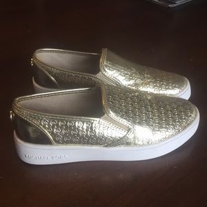Gold Michael Kors slip-ons.